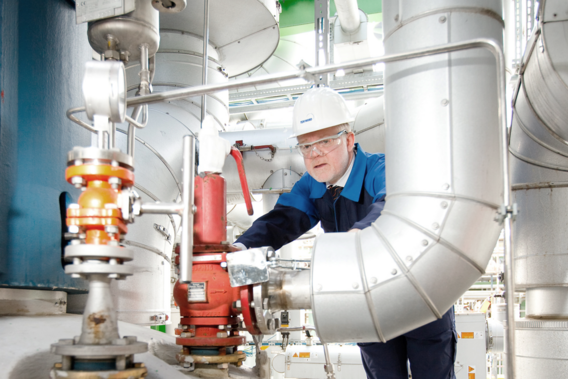 Ein Ingenieur mit Helm prüft eine Industrieanlage.