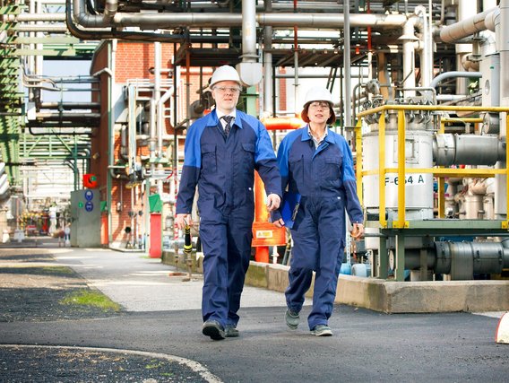 Ingenieure im Chemiepark Zwei Ingenieure in Schutzkleidung gehen durch eine Industrieanlage.